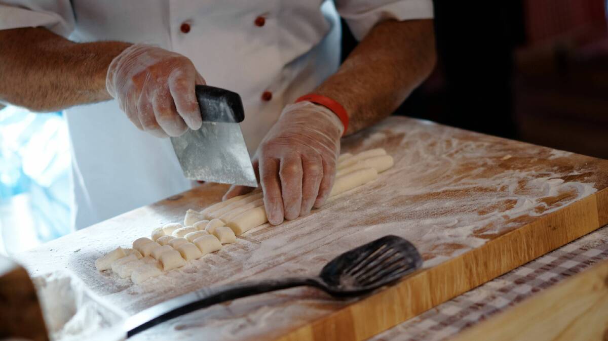 The gnocchi man dicing his white gnocchi; he also sold pastel pink gnocchi naturally coloured with beetroot