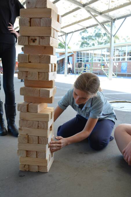 Giant Jenga: Chantel Martin chooses a piece to remove during the game put on my MidCoast Council. Photo: Anne Keen