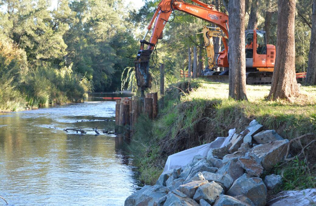 Large wood beams are being driven into the riverbank to help to slow the speed rate of water as it flows down stream during floods.