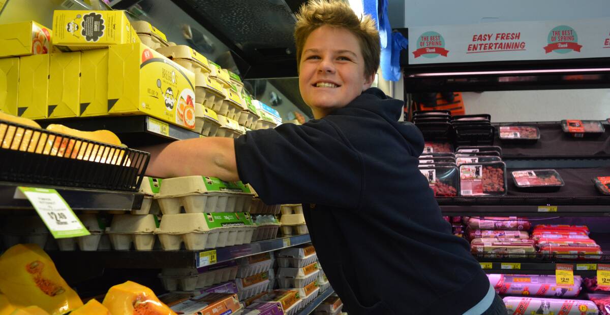 Stacking eggs: Jake Danton carefully places the egg cartons on the shelf, after checking the date, at IGA during his trade experience. Picture: Anne Keen