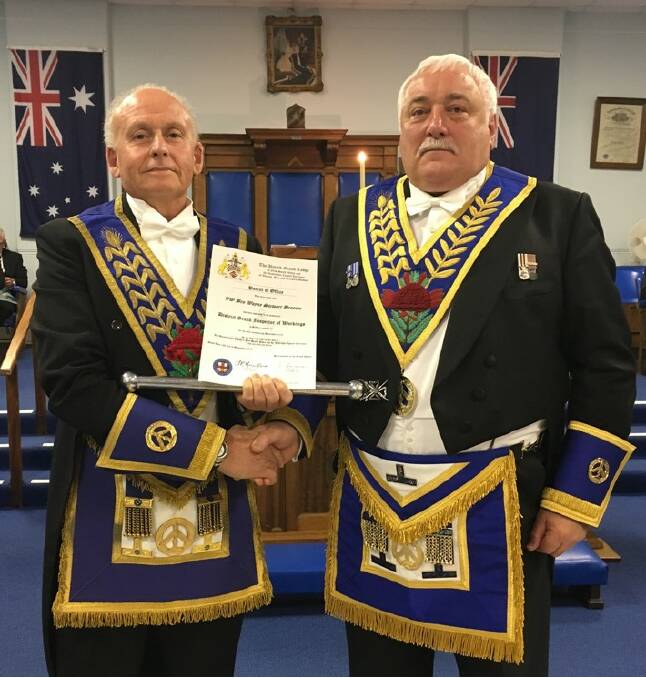 Traditional ceremony: District grand inspector, Wayne Broome receives the over 100-year-old Patent of Office from retiring inspector, Alan Williams. Picture: Supplied