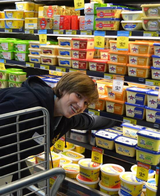 Keeping his cool: Dylan Green gets into his work as he restocks the butter in the fridge at IGA during his 'Try a Trade' experience. Picture: Anne Keen