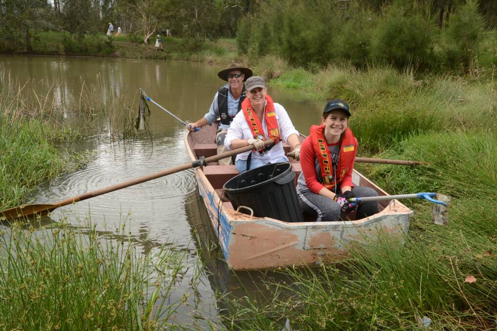 Manning River Times' journalist Ainslee Dennis manned the oars of a boat on Railway Dam as her daughter, Grace McCallum and Aaron Casey worked to fish rubbish from its surface and in the reeds.