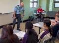 Senior Constable Jonathon Wright showing his prosthetic leg to school children. Picture from video. 