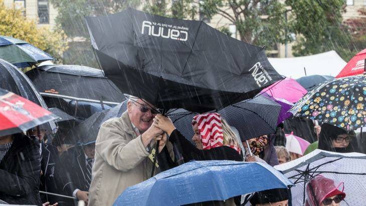 People gather in torrential rain to launch the special Anzac $2 coin in Melbourne. Photo: Jason South