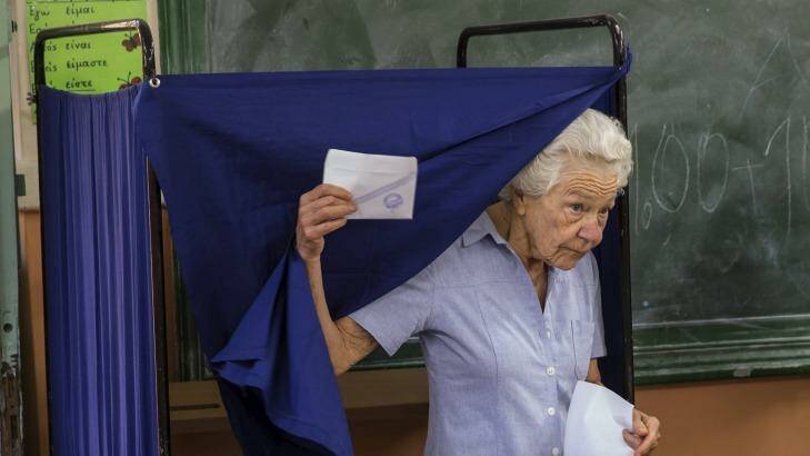 A woman leaves a polling booth to cast her ballot during the referendum in Athens, Greece. Photo: MARKO DJURICA