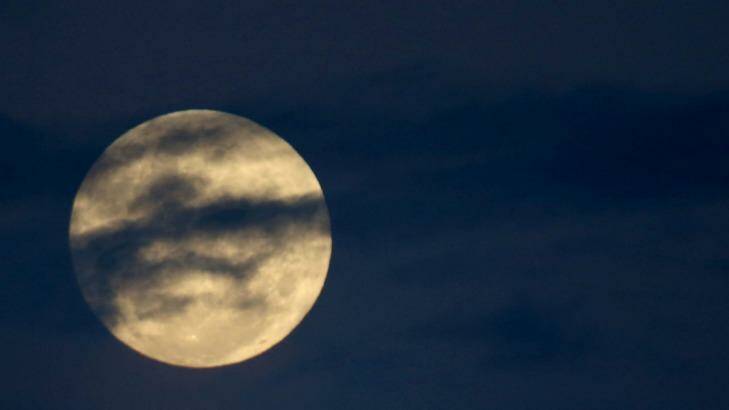 The supermoon peeks through the clouds over Sydney. Photo: James Alcock