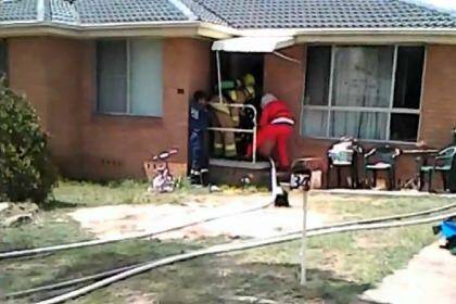 Firefighter Santa Nick Carey and his team rescue a man from a house fire in Maitland during their annual lolly run. Photo: Michael Johnson