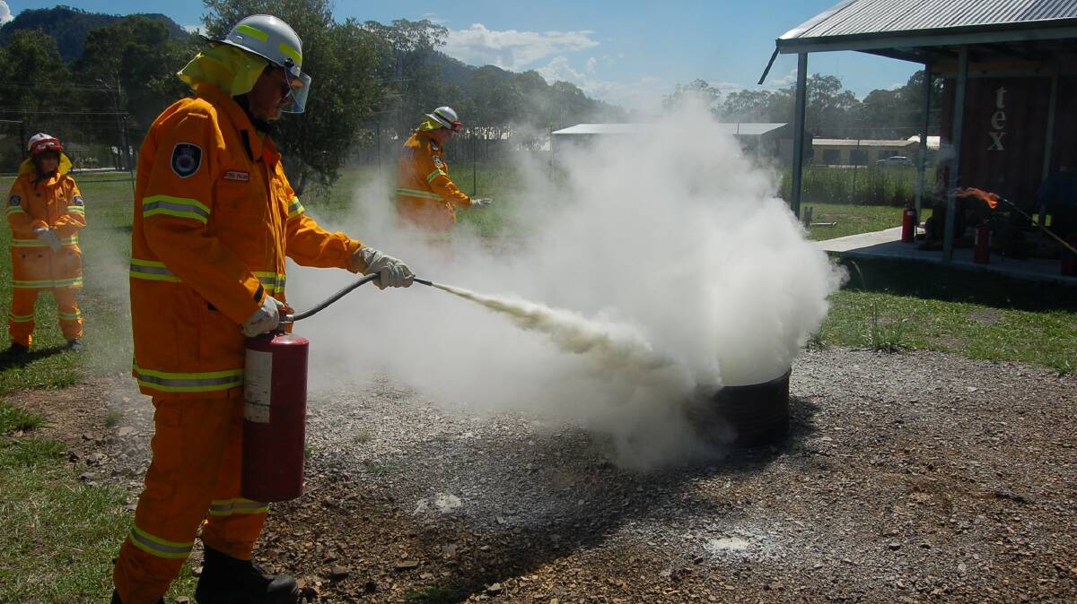 An RFS volunteer douses a fire using an extinguisher.