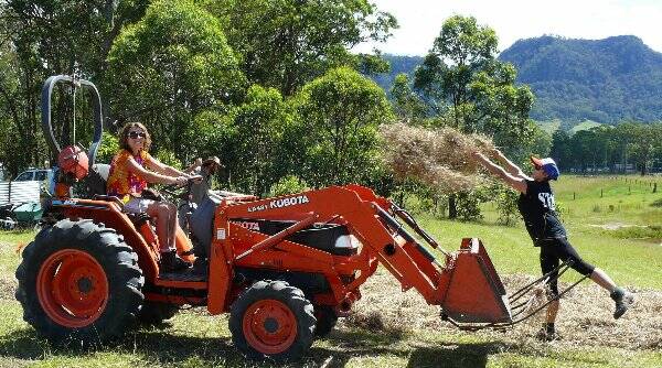 • Shyla Tyrrell on the tractor helps Lisa Folkes, a woolhandler from Dubbo, move a load of mulch at the Tucker Patch.