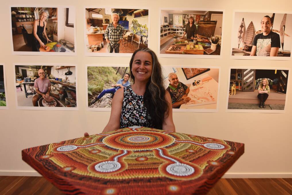 Exhibition: Studio Spaces of the Mid North Coast continues at the Manning Regional Art Gallery until May 13. Gallery director Rachel Piercy holds one of the works and stands in front of images of some of the 16 artists involved.