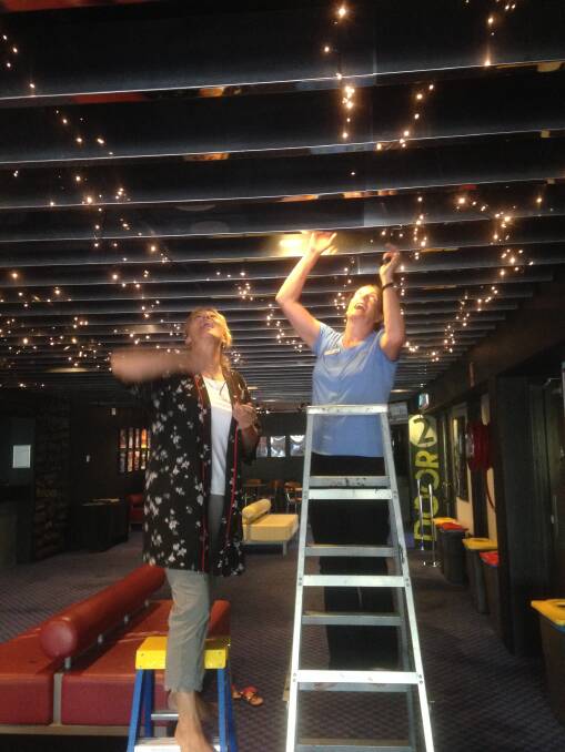 Up in lights: Ann Smith and Kim MacDonald stringing up fairy lights in the Manning Entertainment Centre foyer. Photo: Supplied: