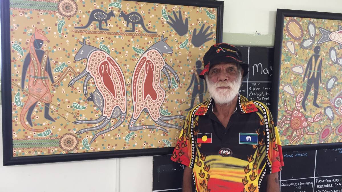 Artist Milton Budge in front of his painting 'Kangaroo man teaching', which depicts a hunter teaching a young boy how to hunt kangaroos.