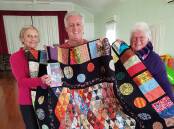 Judy Hopkins and Cath McGovern from Gloucester Patchwork Group with Cath's son David MGovern of the Catholic Mission who purchased the quilt made by his mother. Image supplied.