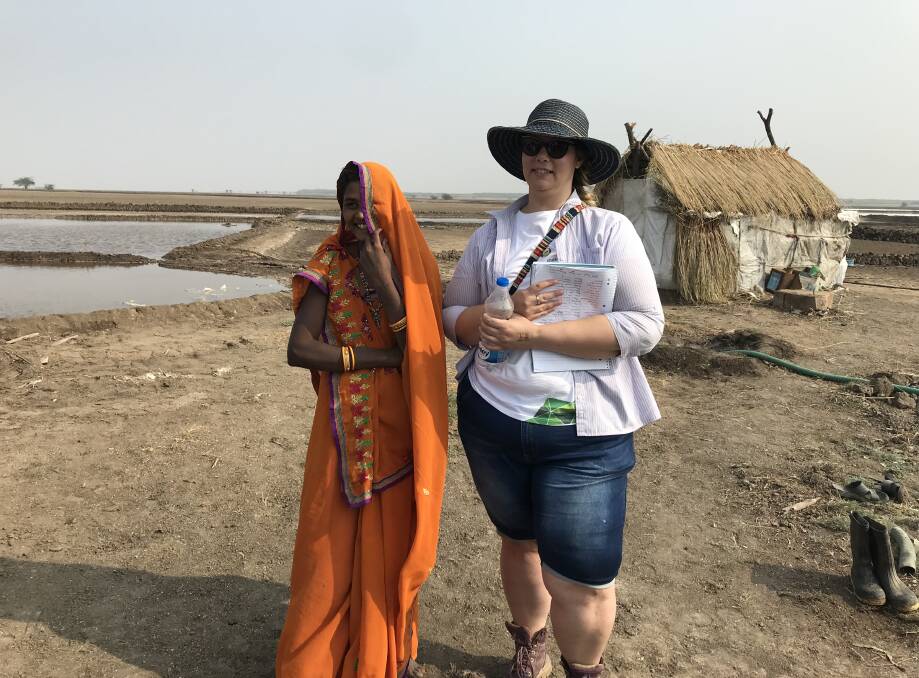 Jade Spencer with one of the women who live on the salt farm, the housing can be seen behind her. 