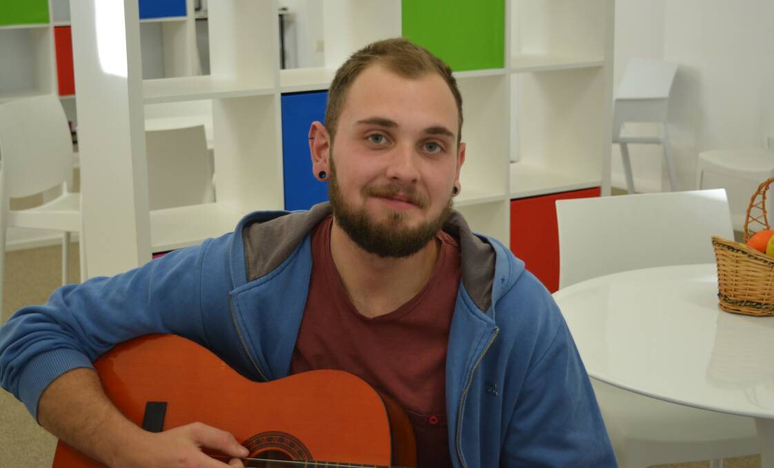Josh Hill plays his guitar at the Bucketts Way Neighbourhood Centre where he volunteers teaching others how to play.