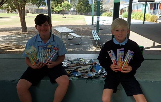 Cody Howard and Kayden Schumann show off all the toothbrushes donated by their classmates.