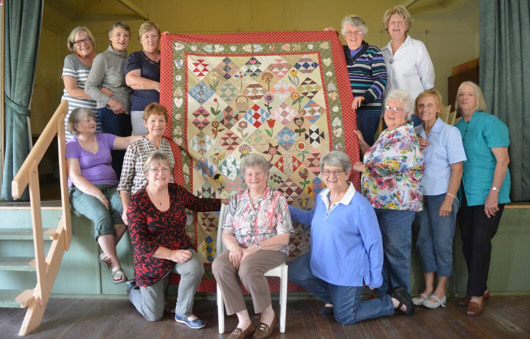 Gloucester Patchwork Group members show off the quilt by Cath McGovern which will be raffled to raise funds for The Cottage.