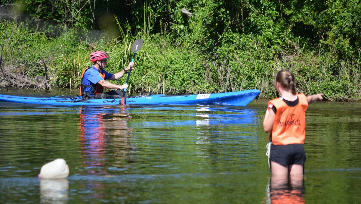 Volunteers can be found at various locations around the track, like this one at the end of the kayak leg directing the competitor to the shore in 2016. Photo Anne Keen