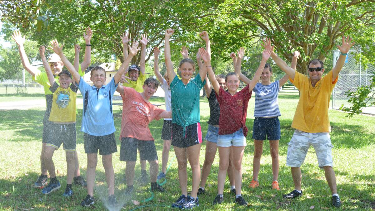 The students and their teacher, Rob Seale, enjoy a cool down under a sprinkler in the park. Photo Anne keen