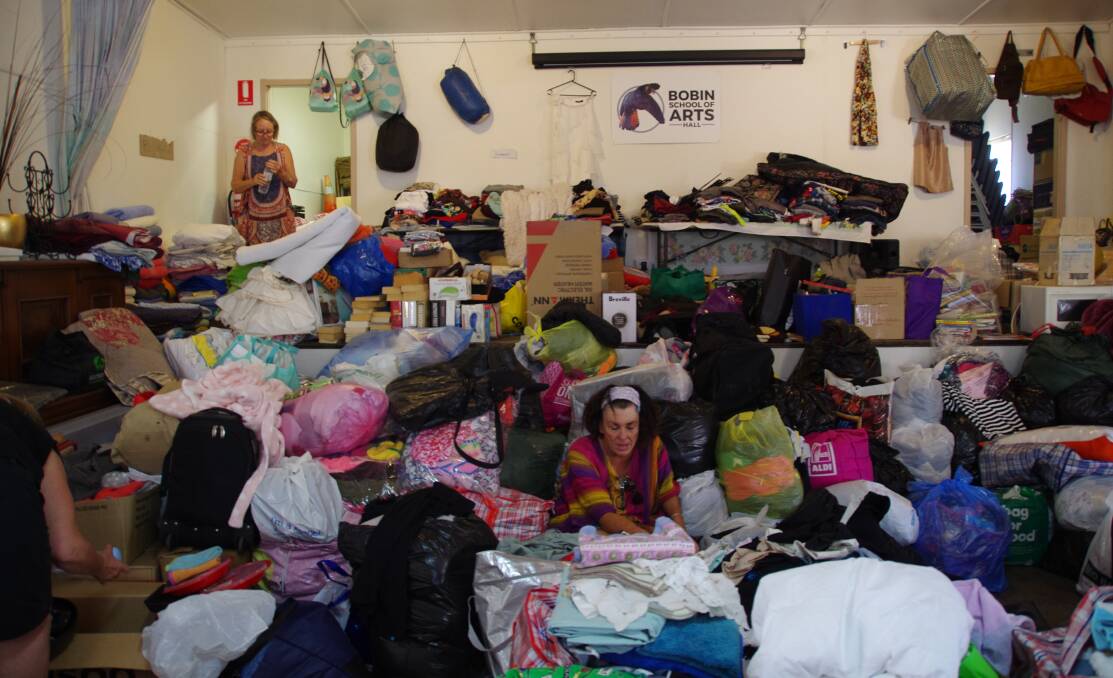 A sea of clothes: volunteers at Bobin hall sort the clothes from the Shell Harbour donation. Photo: Julia Driscoll